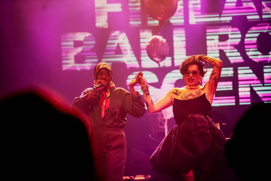 Two performers in front of a screen reading Finland Ballroom Scene
