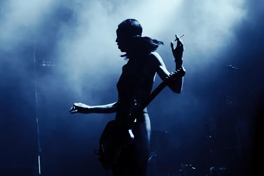 A performer in silhouette in blue smoke and beams