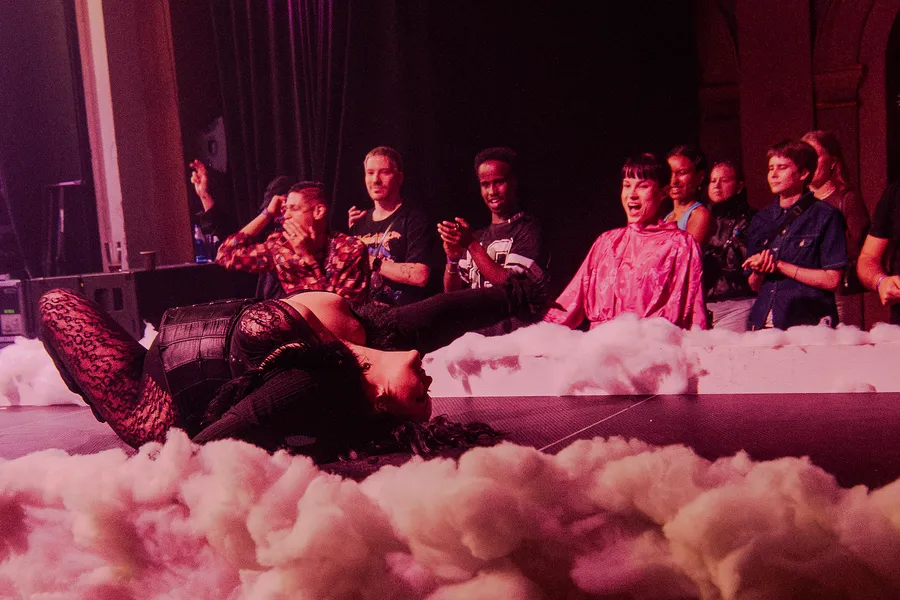 A row of people sitting along the edge of a stage banked with cloud