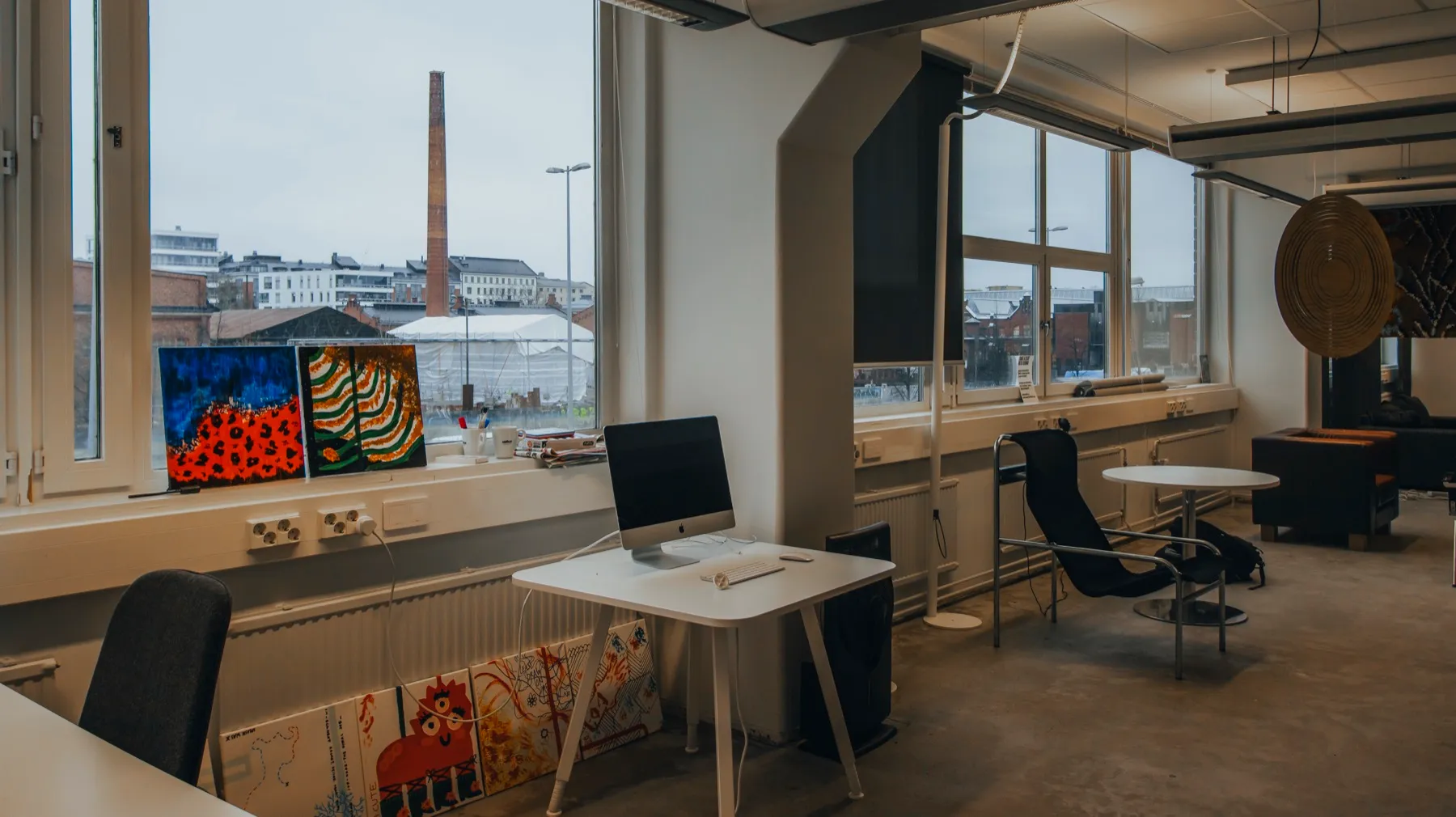 The 2nd-floor co-creation space: desks and lounge chairs by tall windows.