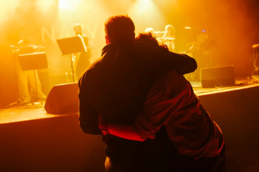 Two people embracing, lit from behind in gold