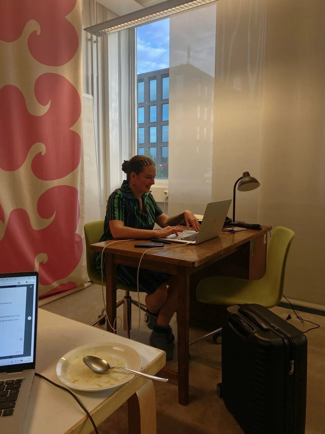 Someone working on a laptop at a desk by the window