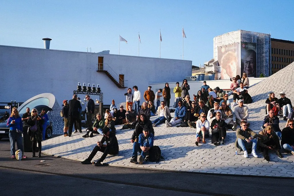 A crowd sitting on the sunlit steps of the Lasipalatsi yard