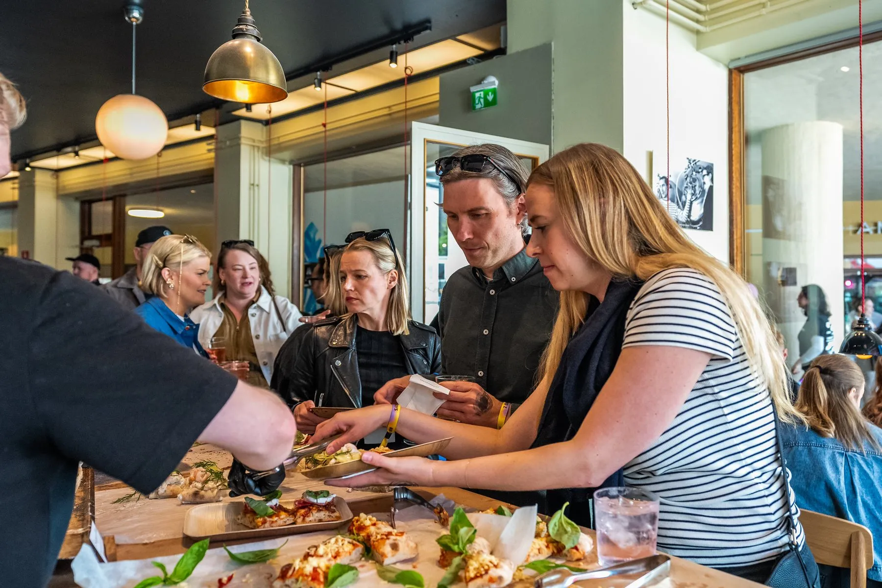People reaching for pizza across a long shared table