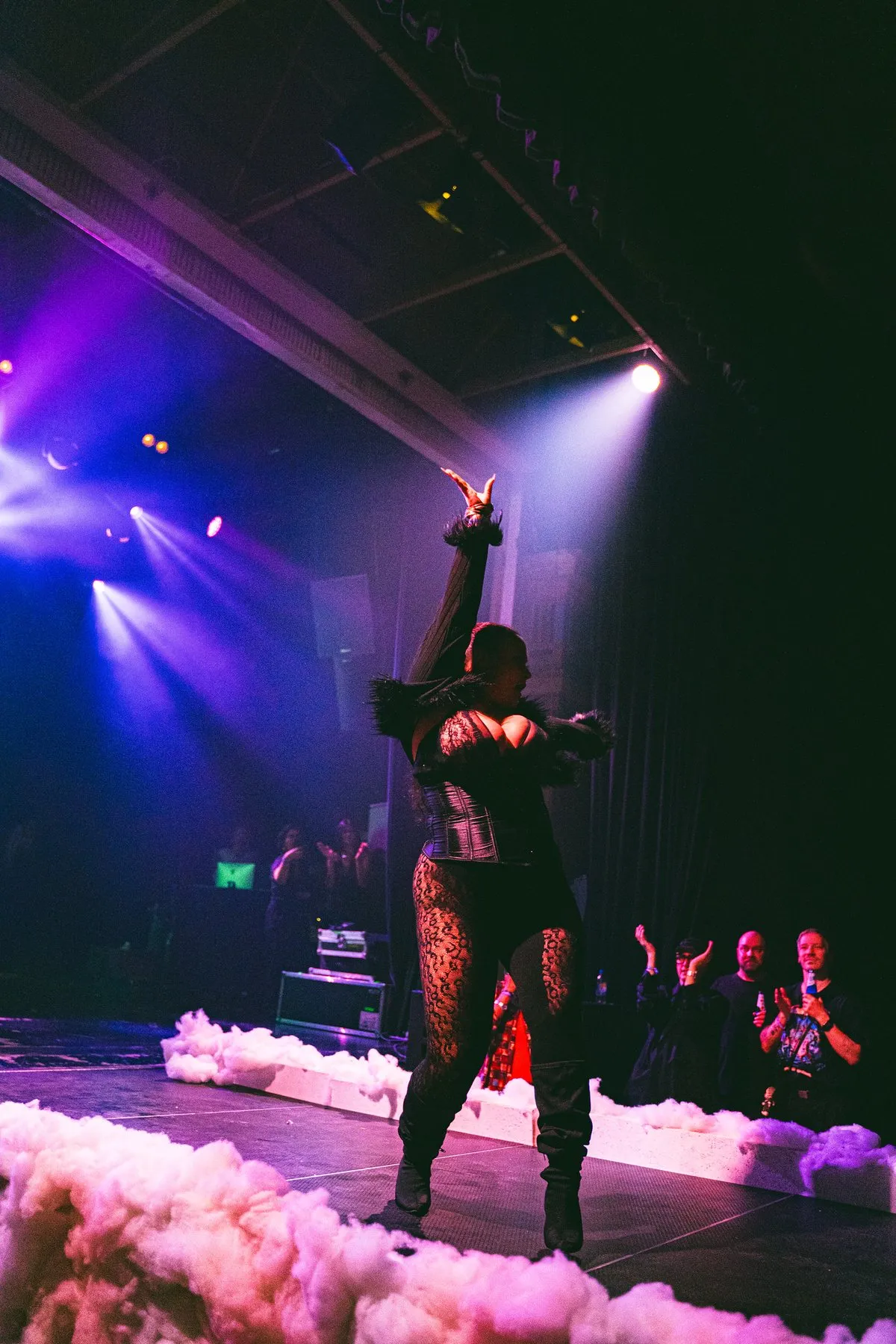 A performer on a smoke-covered stage under purple light