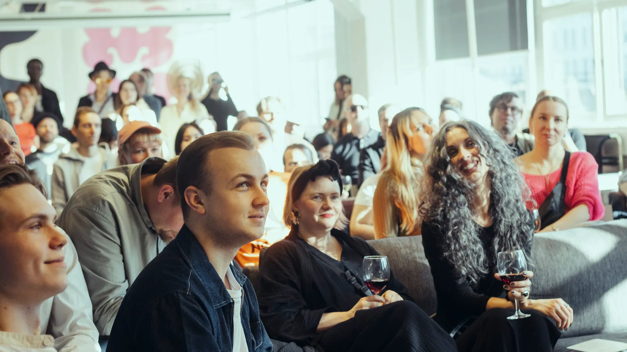 An audience listening, glasses in hand, at the ODDspace opening