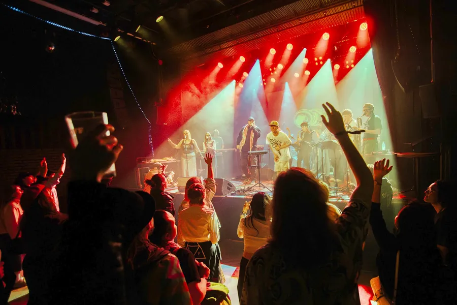 A full band on stage seen over the heads of the crowd